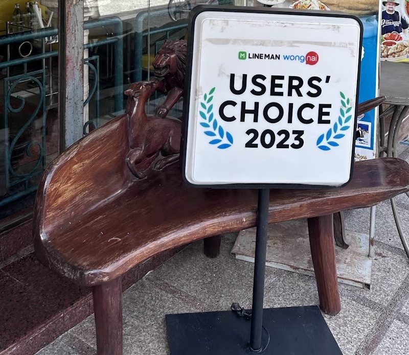 ป้าย Users' Choice 2023 ของ LINE MAN Wongnai หน้าร้าน ข้างม้านั่งไม้