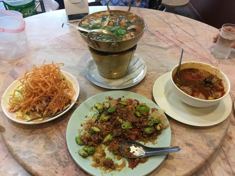 สำรับบนโต๊ะหินอ่อน ต้มยำในหม้อไฟทองเหลือง ยำมะม่วง สะตอผัด และแกง
