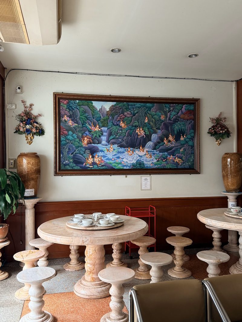 โต๊ะกลมหินอ่อนกับเก้าอี้สตูล ใต้ภาพวาดทิวทัศน์บนผนังร้าน